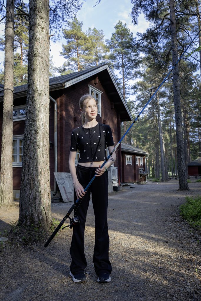 Säde esittelee onkea luontotalon edessä, päällään mustaa.